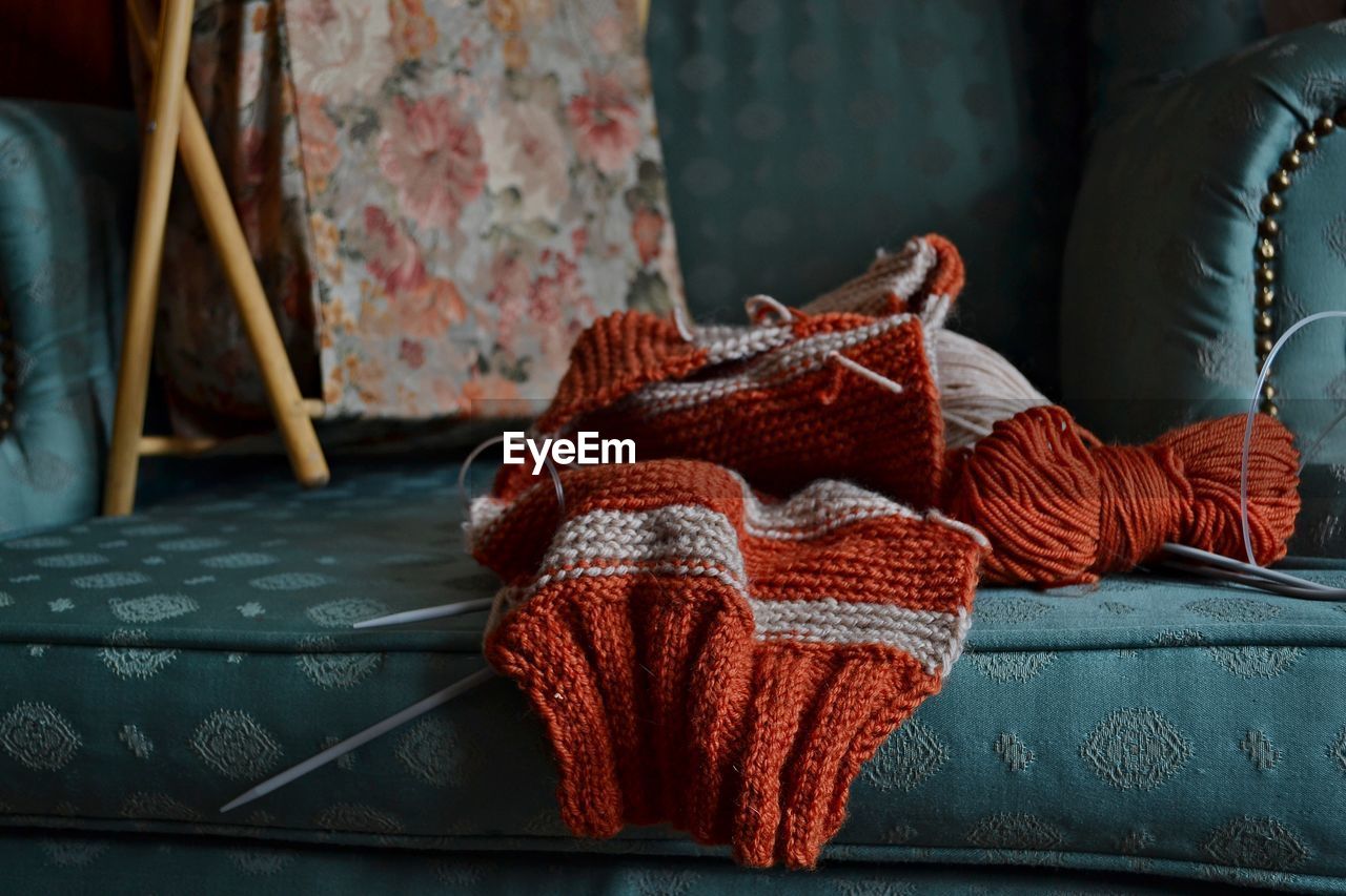 Close-up of wool and knitting needle on sofa