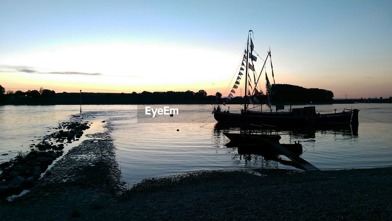 Silhouette of yacht on lake at sunset