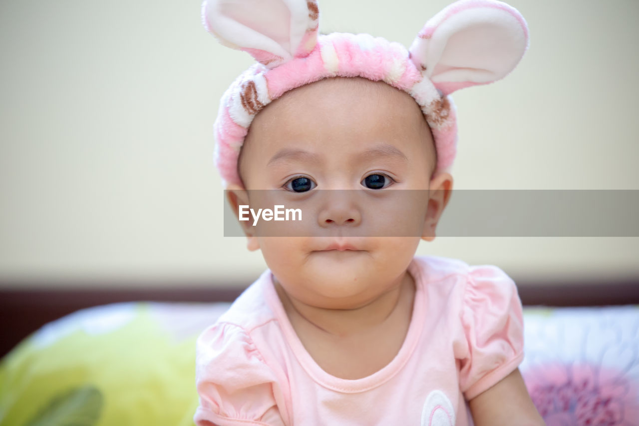 Cute baby girl wearing bunny ears headband at home