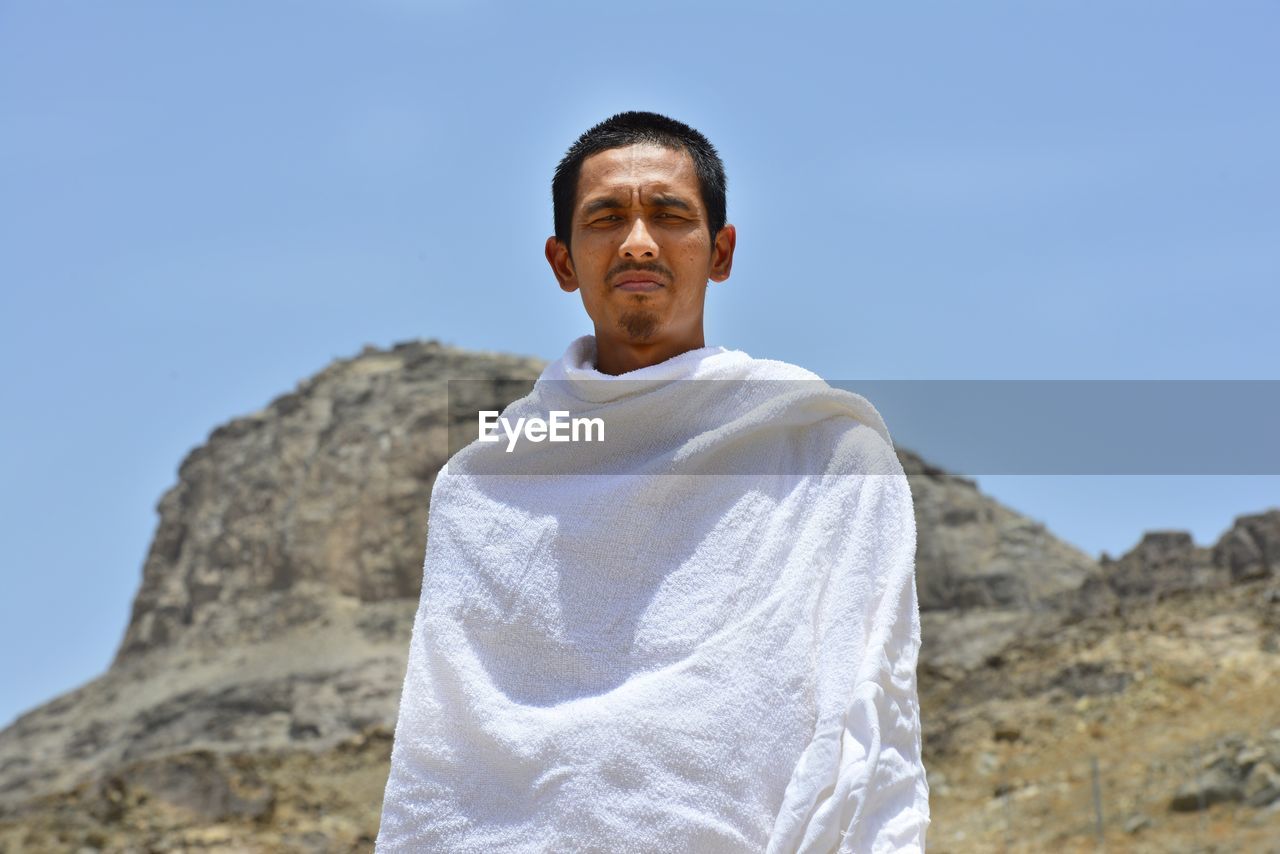 Portrait of man standing against clear blue sky