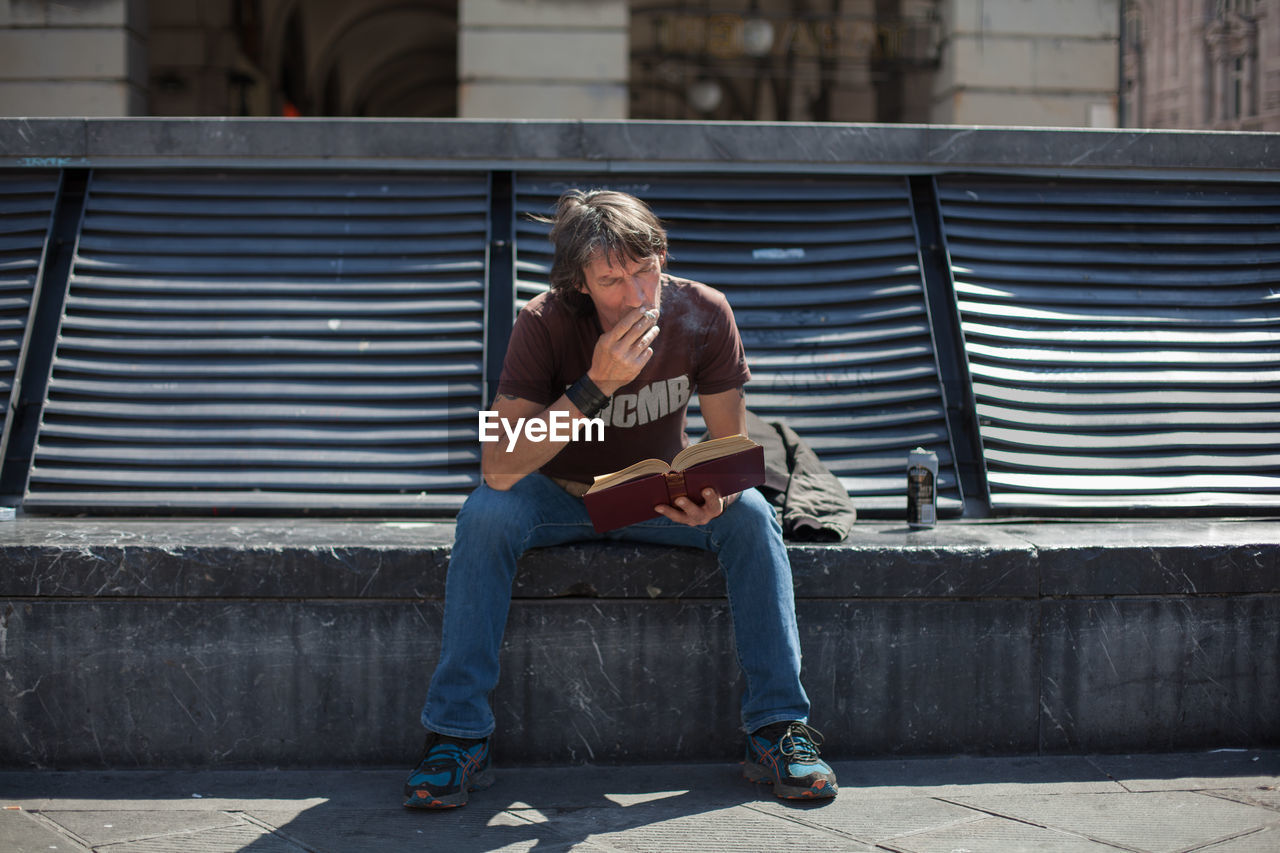 Man reading book while smoking cigarette