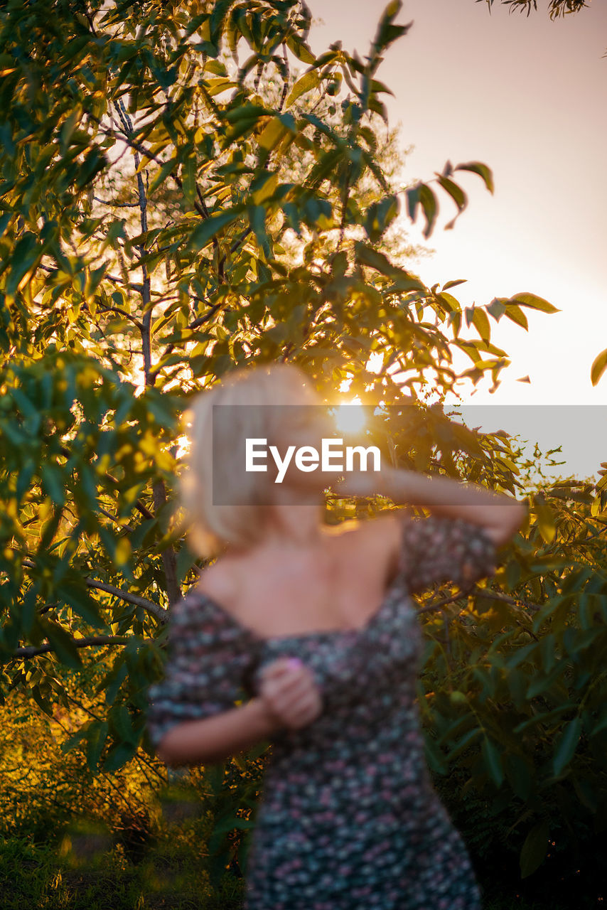 Rear view of woman standing against trees