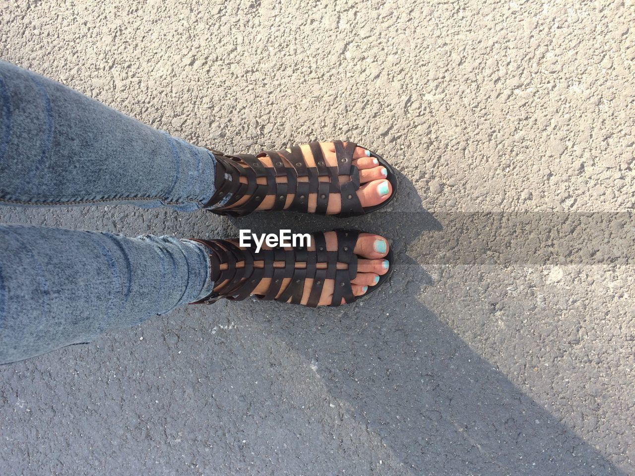 Low section of woman wearing fashionable sandals while standing on street