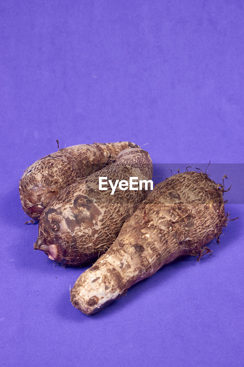 Closeup of taro root vegetable, eddo malanga, purple background