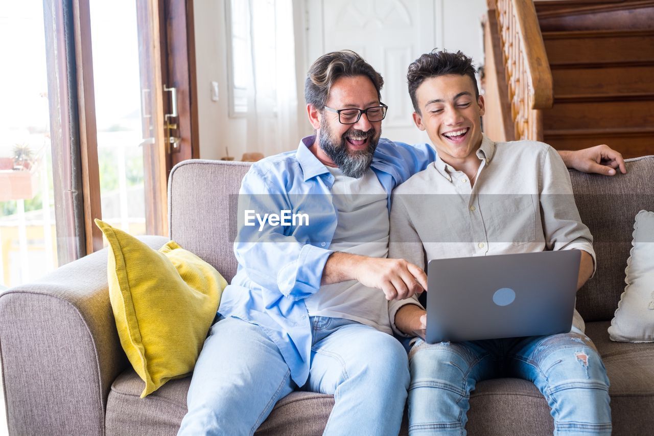 Smiling father using laptop with son