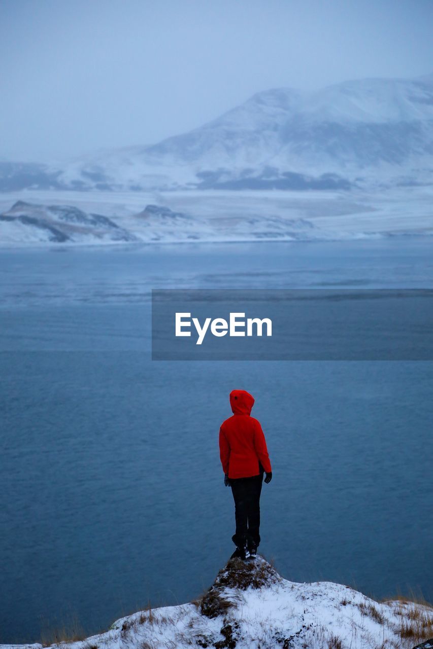 Rear view of person on snowcapped mountain against sky