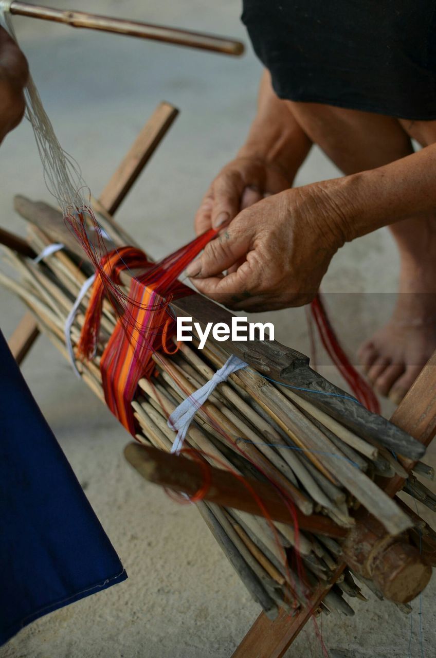 Cropped image of person weaving with threads