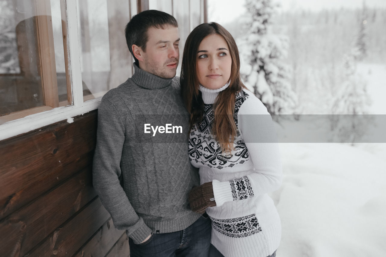 Couple standing by window during winter