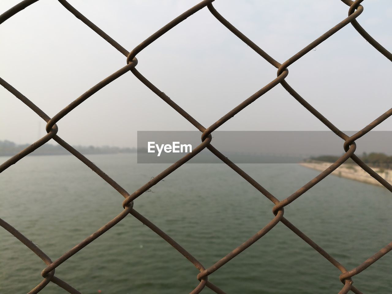 Close-up of chainlink fence against sea