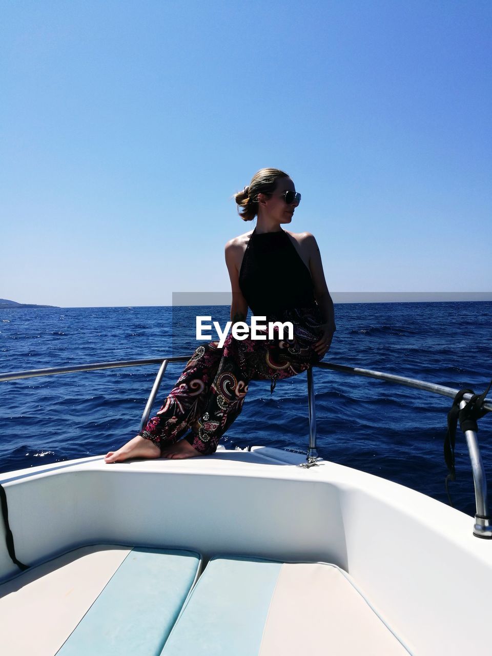 MAN SITTING ON BOAT AGAINST CLEAR SKY