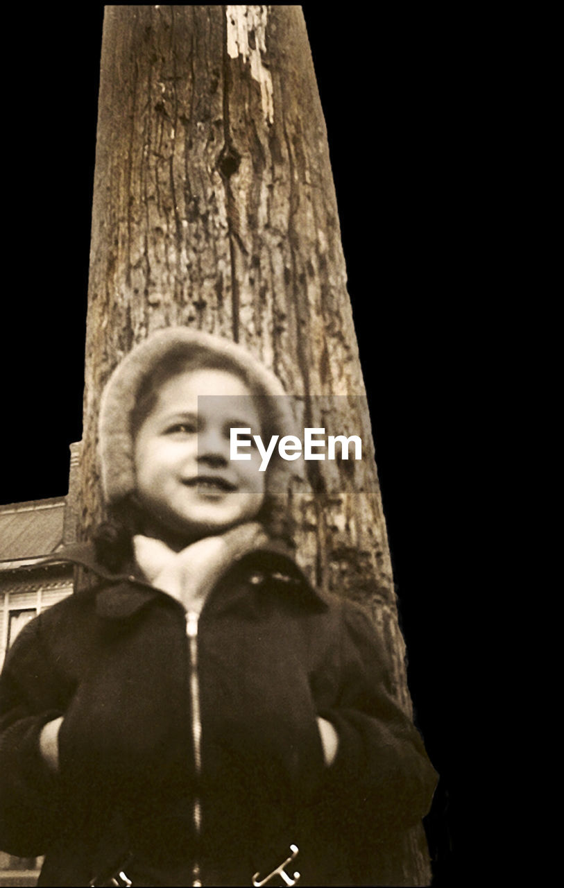 PORTRAIT OF HAPPY SMILING BOY AGAINST TREE TRUNK