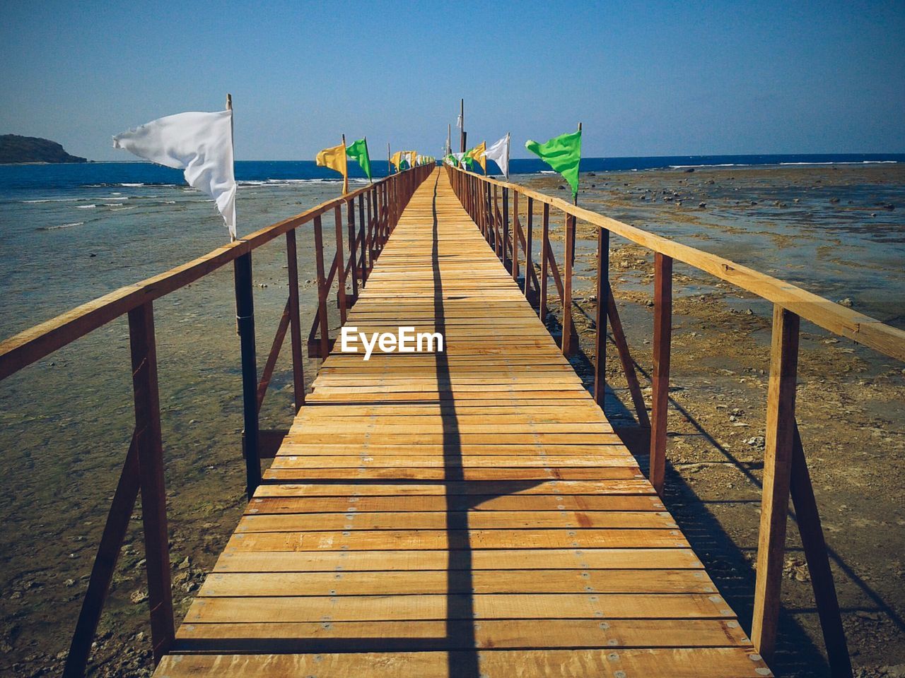 Pier leading towards sea against clear sky