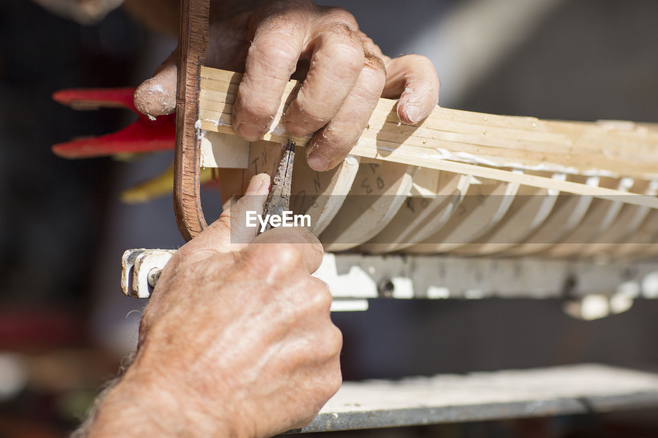 Close-up of man working on wooden boat model