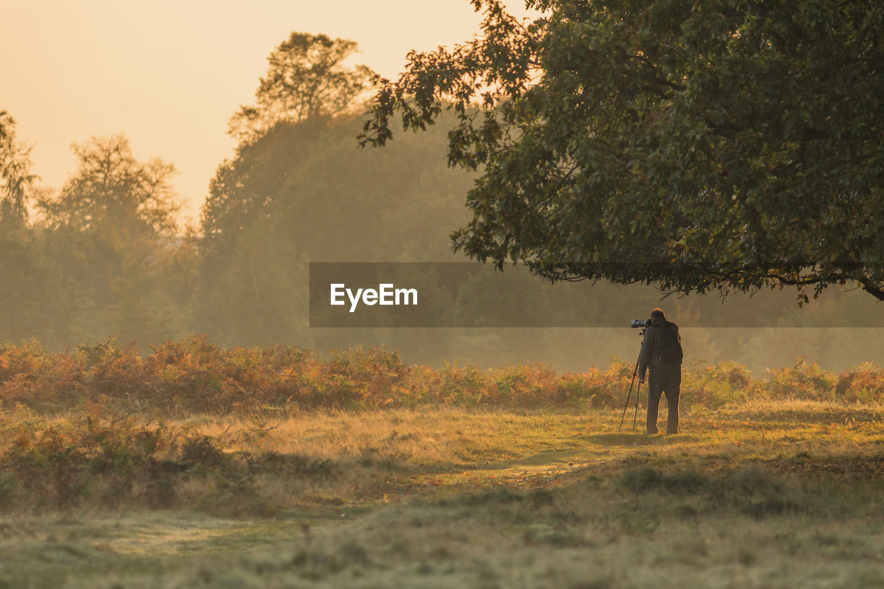 Man photographing field during sunset