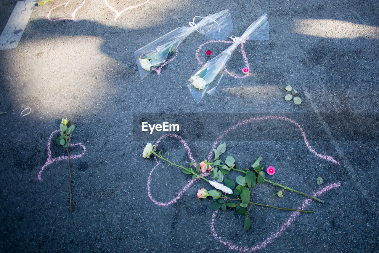 High angle view of bouquets and tea lights on chalk drawing at road after terrorist attack