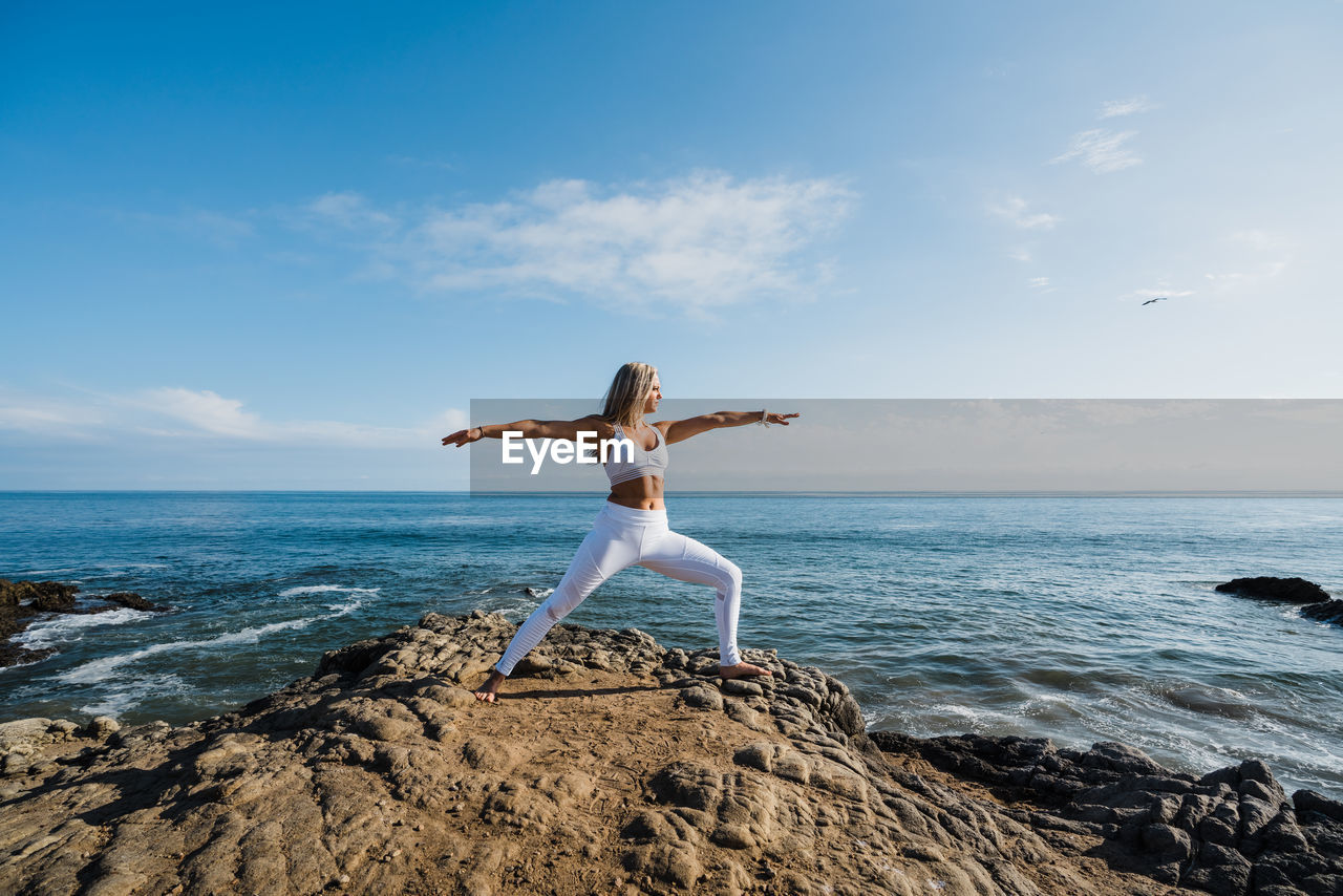 Young woman doing yoga exercises on the rocky beach