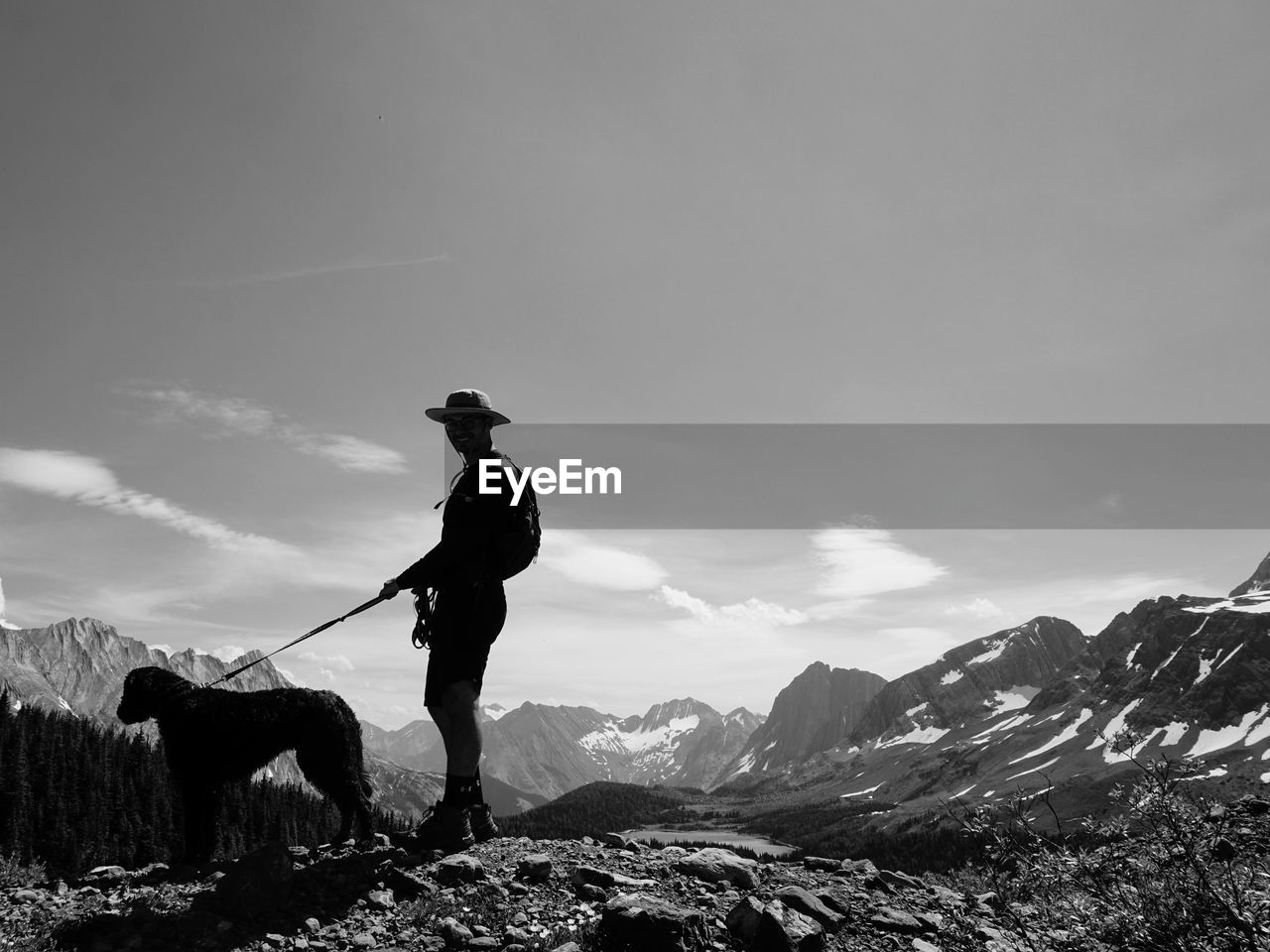 Man standing on mountain against sky with dog