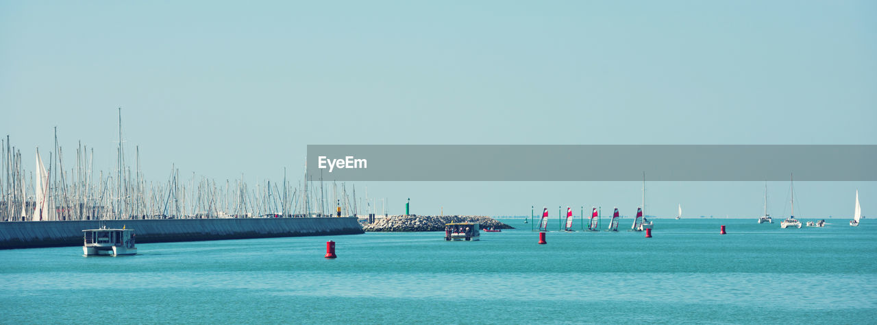 GROUP OF PEOPLE ON SAILBOAT AGAINST CLEAR SKY