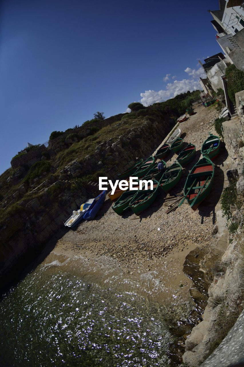 High angle view of fishing boats moored in canal against blue sky