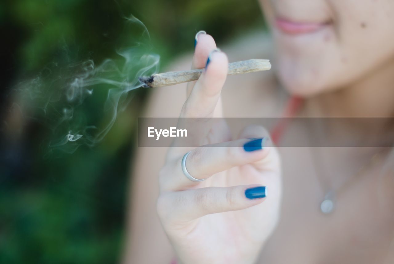 Midsection of woman smoking marijuana joint