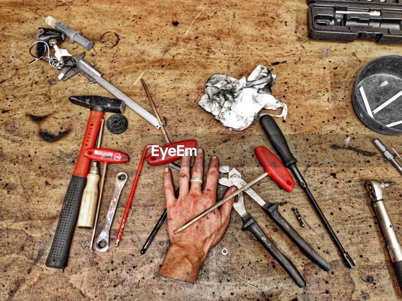 Digital composite image of hand and tools on wooden table