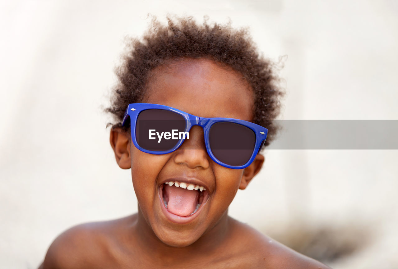 Close-up portrait of boy with mouth open wearing sunglasses