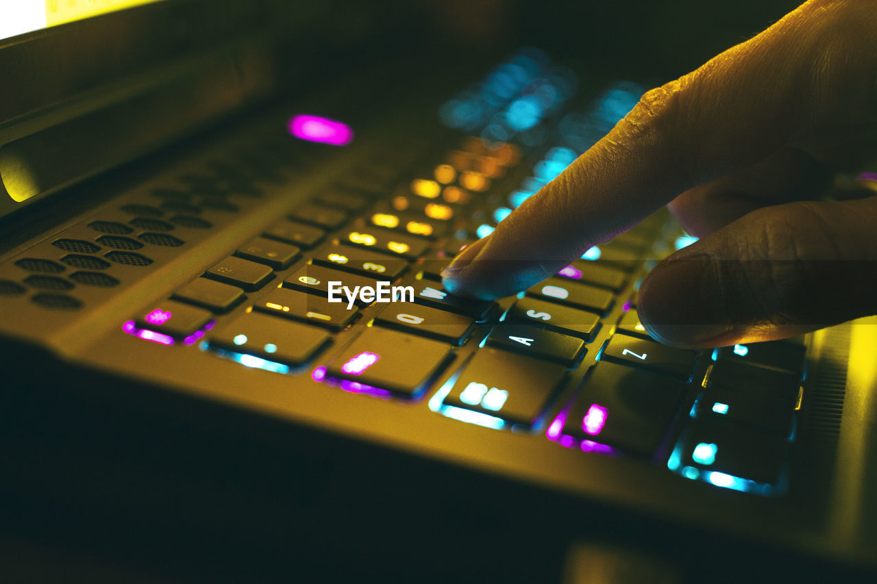 Close-up of hand using illuminated computer keyboard
