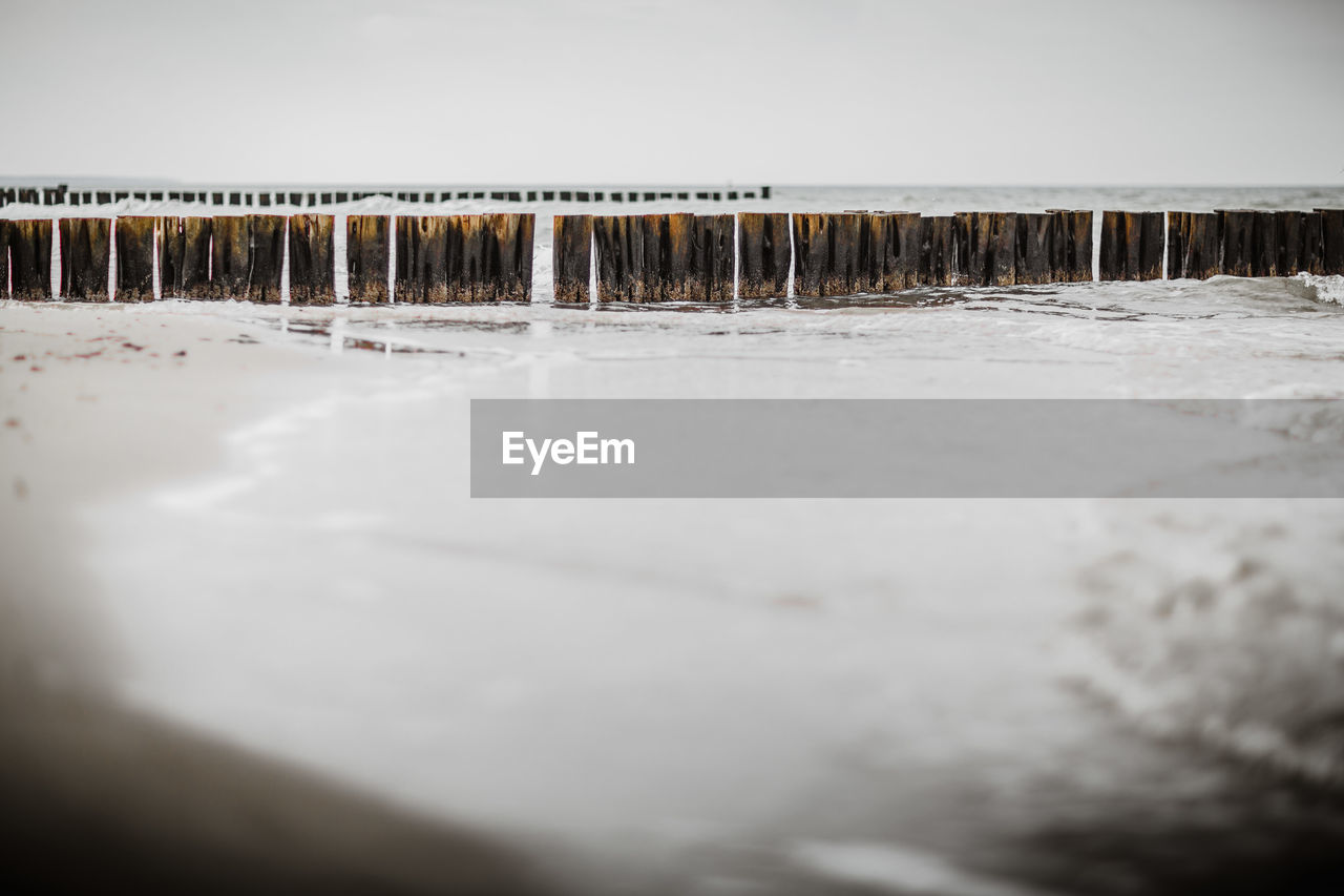 Close-up of snow on beach against sky