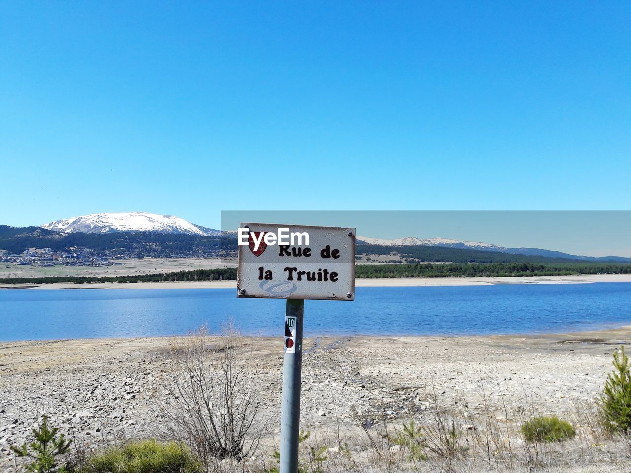 Information sign by mountains against clear blue sky