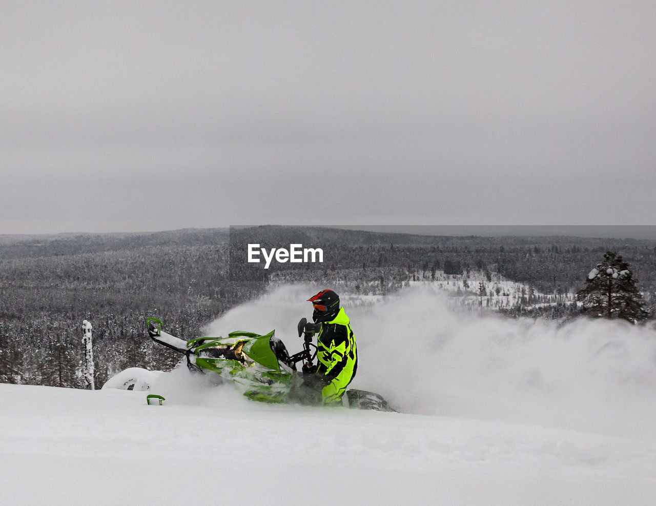 Man snowmobiling on field against cloudy sky