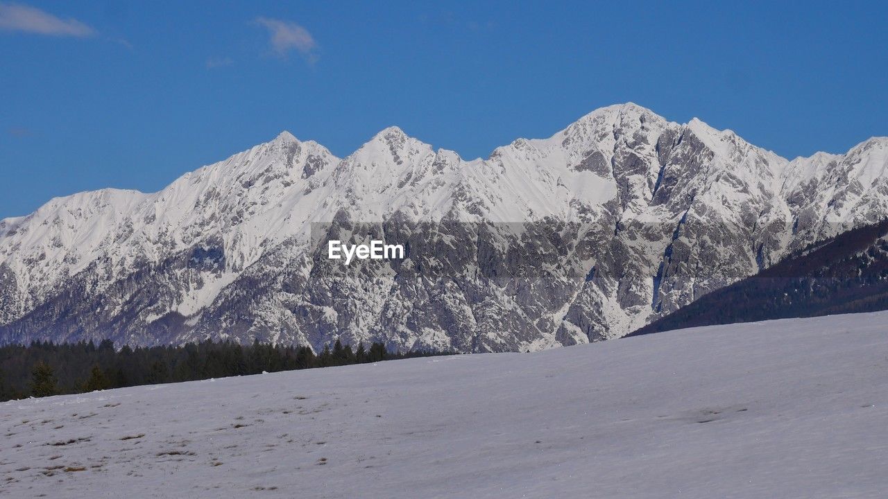 snow, mountain, cold temperature, winter, scenics - nature, mountain range, sky, beauty in nature, environment, landscape, ridge, snowcapped mountain, nature, piste, tranquil scene, blue, no people, land, tranquility, tree, travel destinations, day, pine tree, non-urban scene, coniferous tree, plant, plateau, clear sky, travel, white, pinaceae, massif, summit, outdoors, pine woodland, mountain peak, frozen, mountain pass, tourism, forest, idyllic, cloud