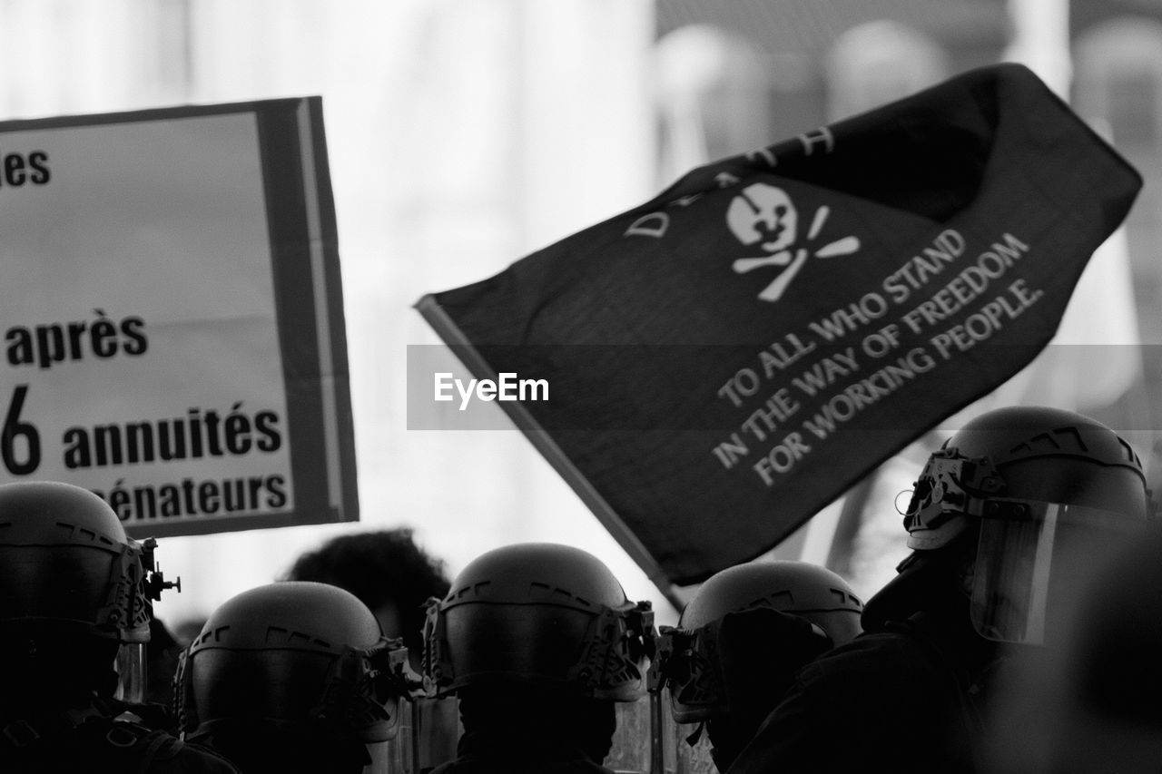 black, black and white, monochrome, text, monochrome photography, communication, protest, crowd, western script, law, white, police force, sign, clothing, government, group of people, protestor, person