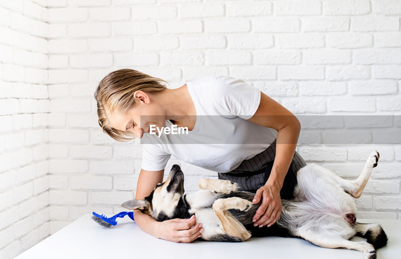 Woman with dog against wall