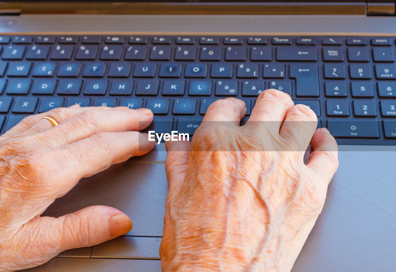 Cropped hands of senior woman using laptop