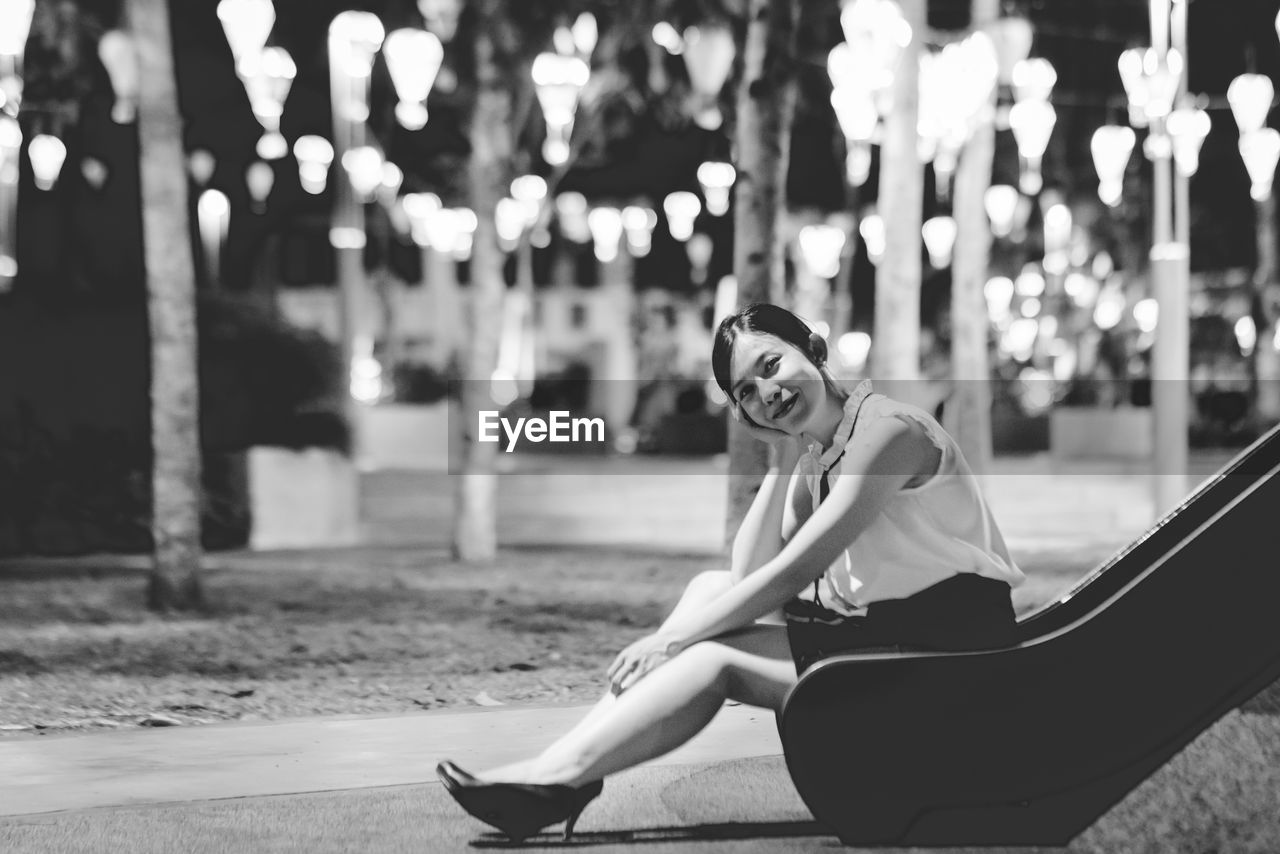 Portrait of smiling woman sitting on slide at park