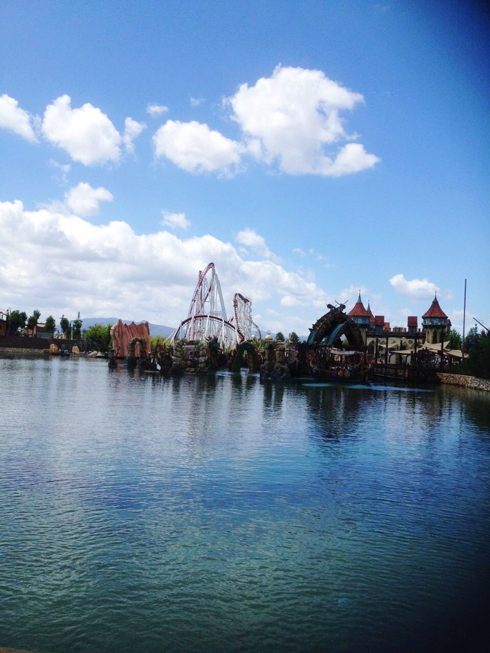 VIEW OF FERRIS WHEEL BY RIVER AGAINST SKY