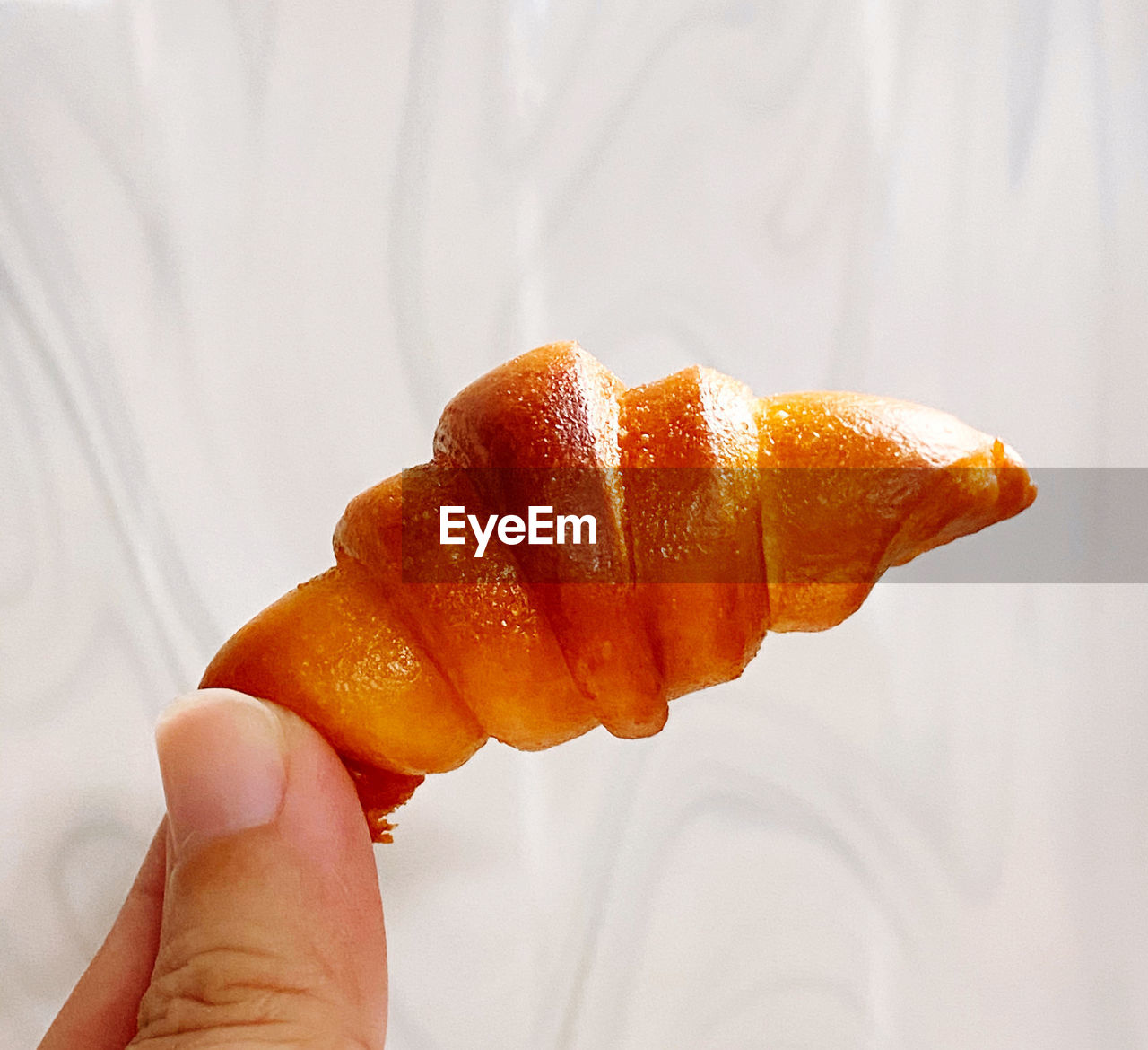 CLOSE-UP OF HAND HOLDING ORANGE SLICE