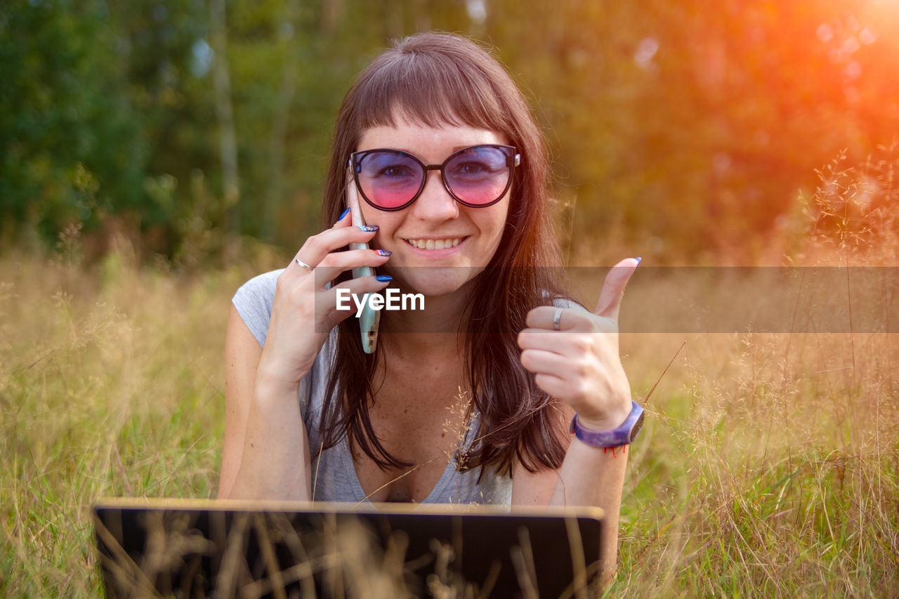 portrait of young woman wearing sunglasses while sitting on grass