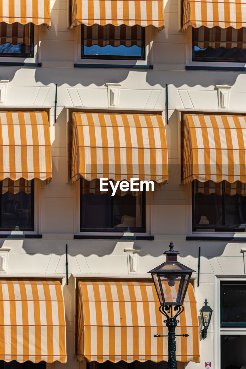 Leiden, netherlands, lamppost with orange overhang sunshade and modern building facade 