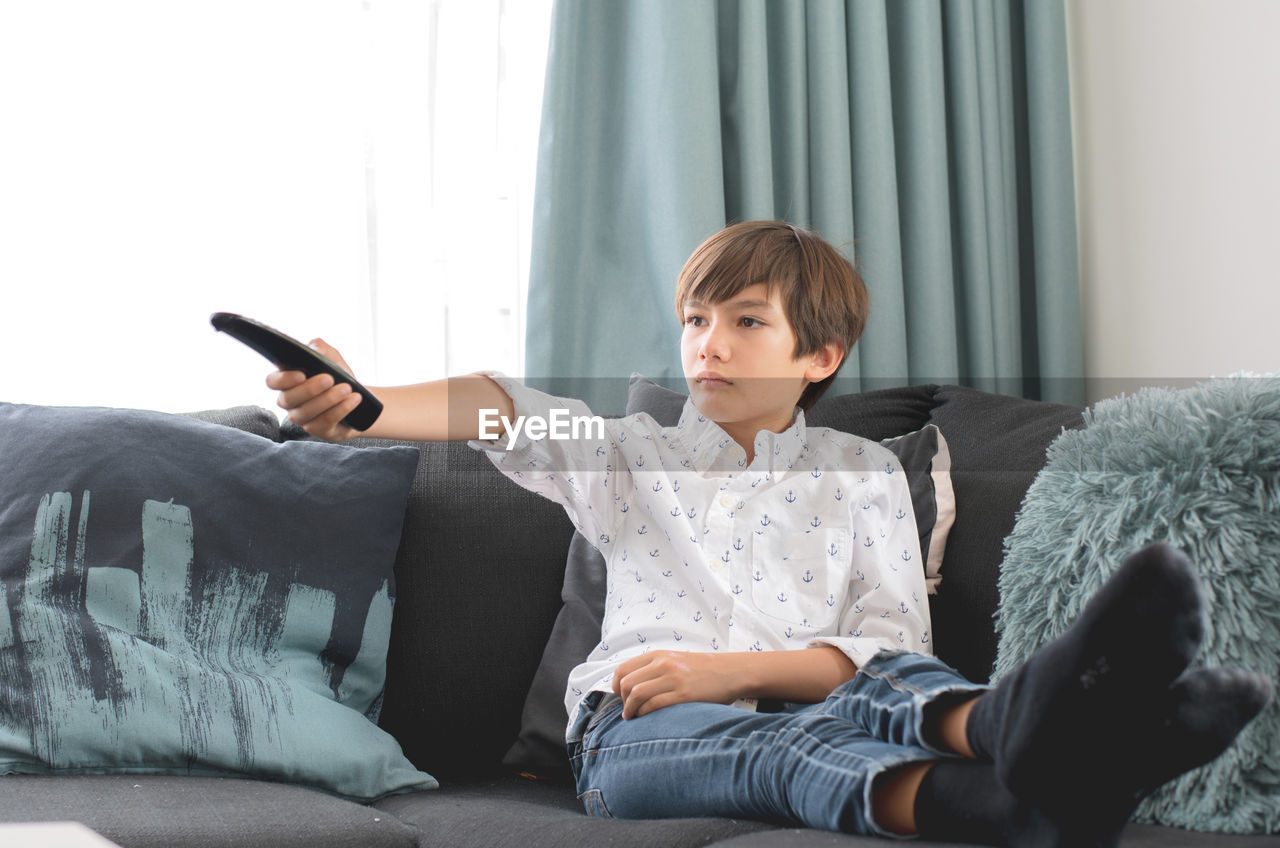 REAR VIEW OF BOY SITTING ON SOFA