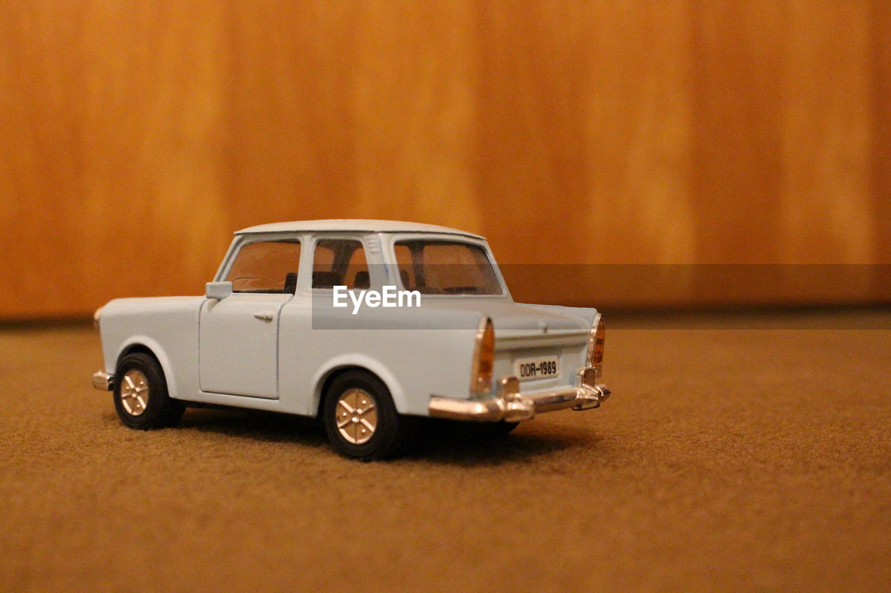 CLOSE-UP OF TOY CAR AGAINST YELLOW RED WALL