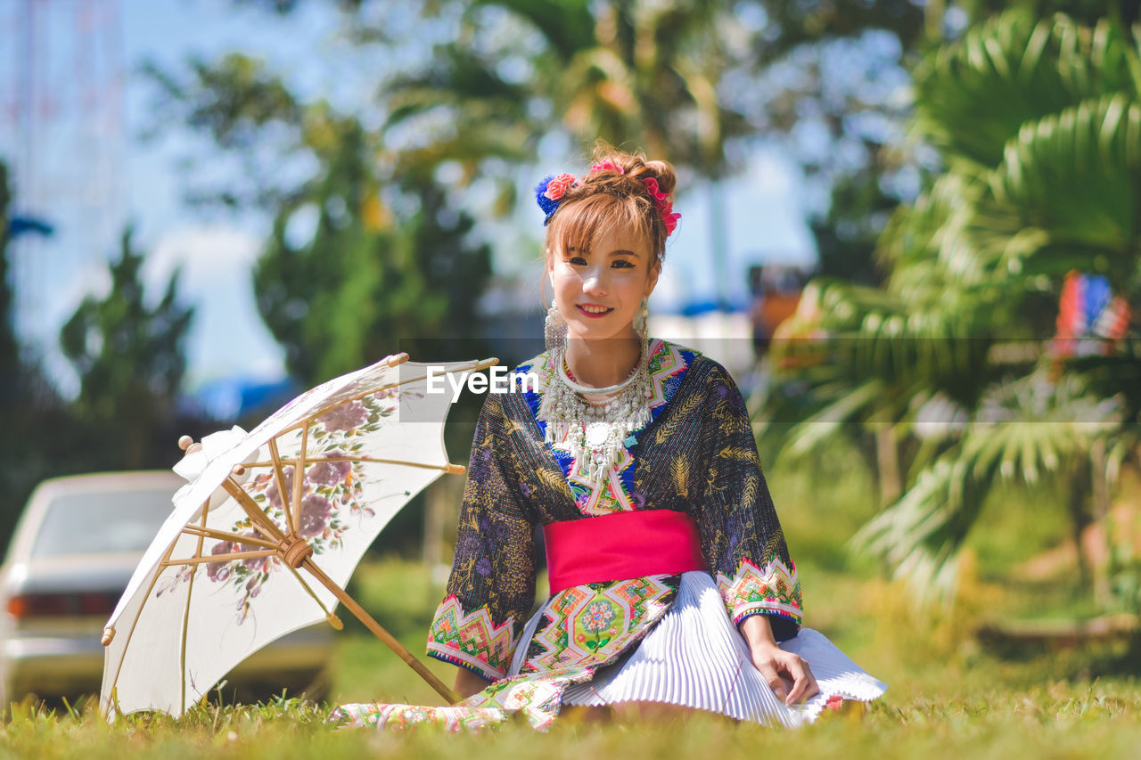 PORTRAIT OF SMILING YOUNG WOMAN WITH UMBRELLA