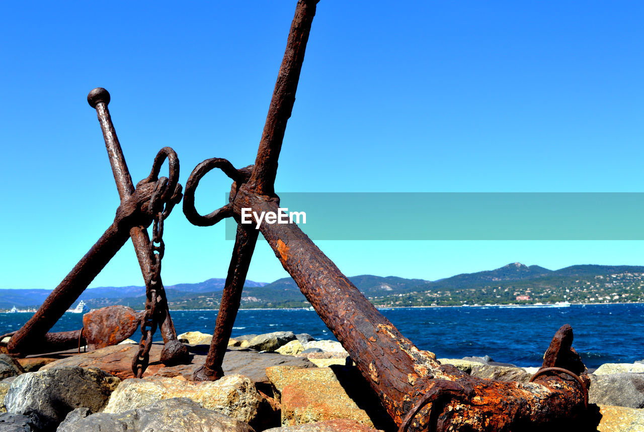 CLOSE-UP OF RUSTY METAL ON SEA AGAINST CLEAR SKY