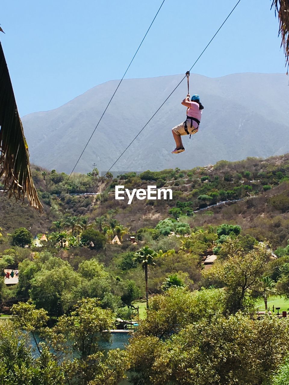 Low angle view of woman on zip line against mountains