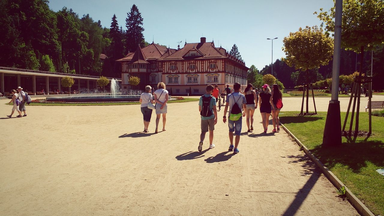 PEOPLE WALKING ON BUILT STRUCTURE AGAINST TREES