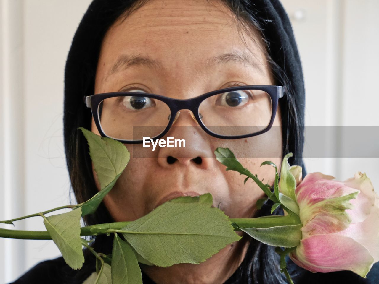 Close-up portrait of shocked woman with rose at home