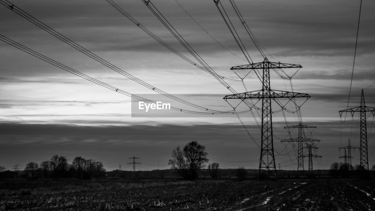 Electricity pylon on field against sky