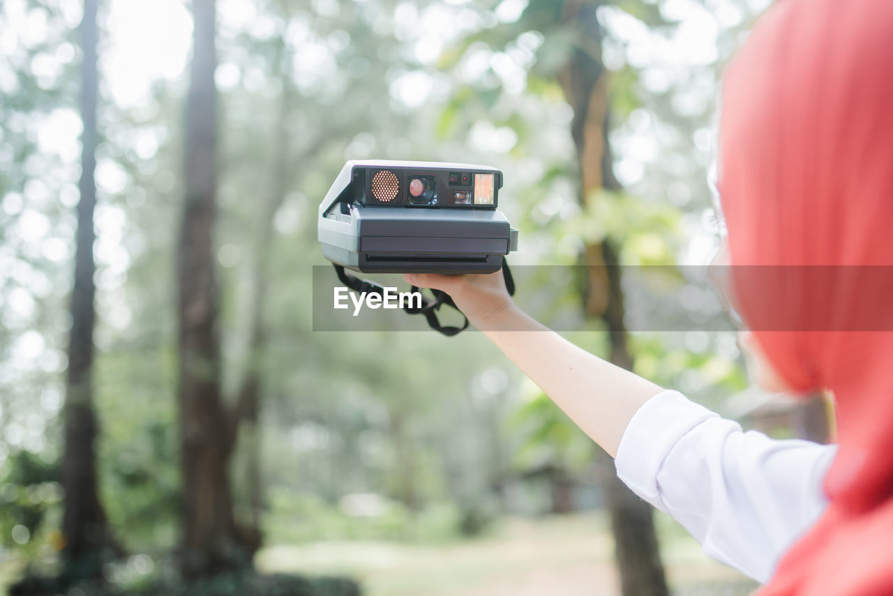 Cropped image of woman photographing while standing outdoors