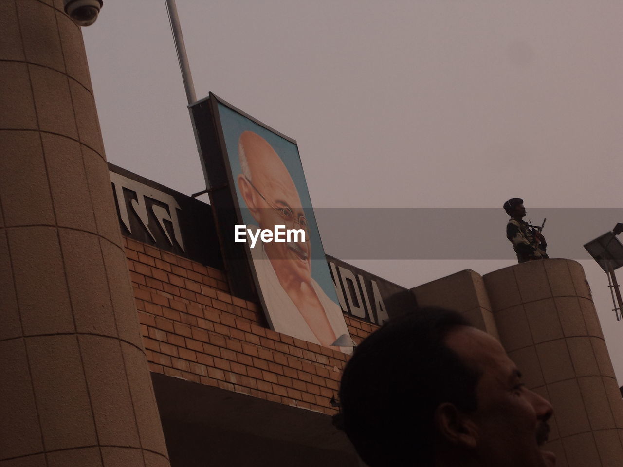 LOW ANGLE VIEW OF MAN PHOTOGRAPHING ON ROOF