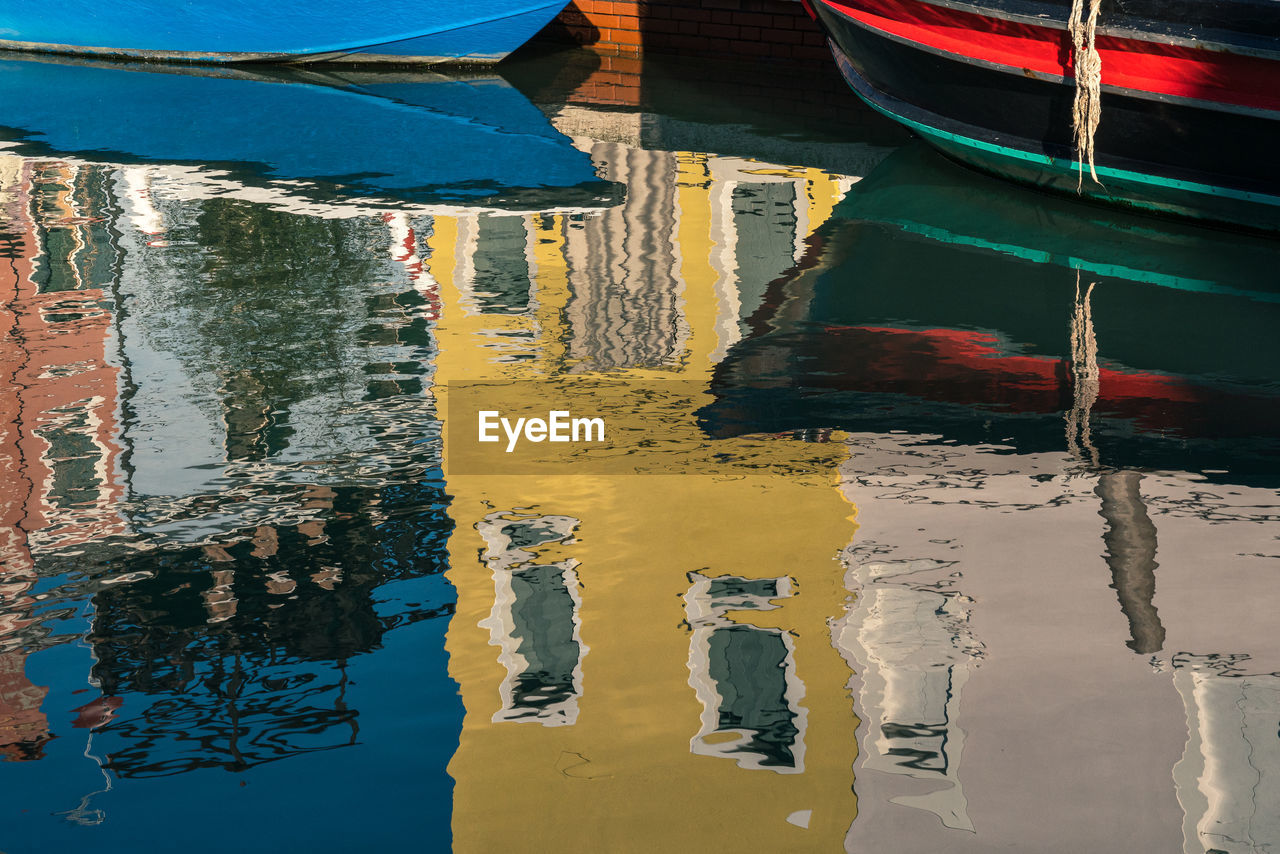 Reflection of italian buildings on water of canal with boats.